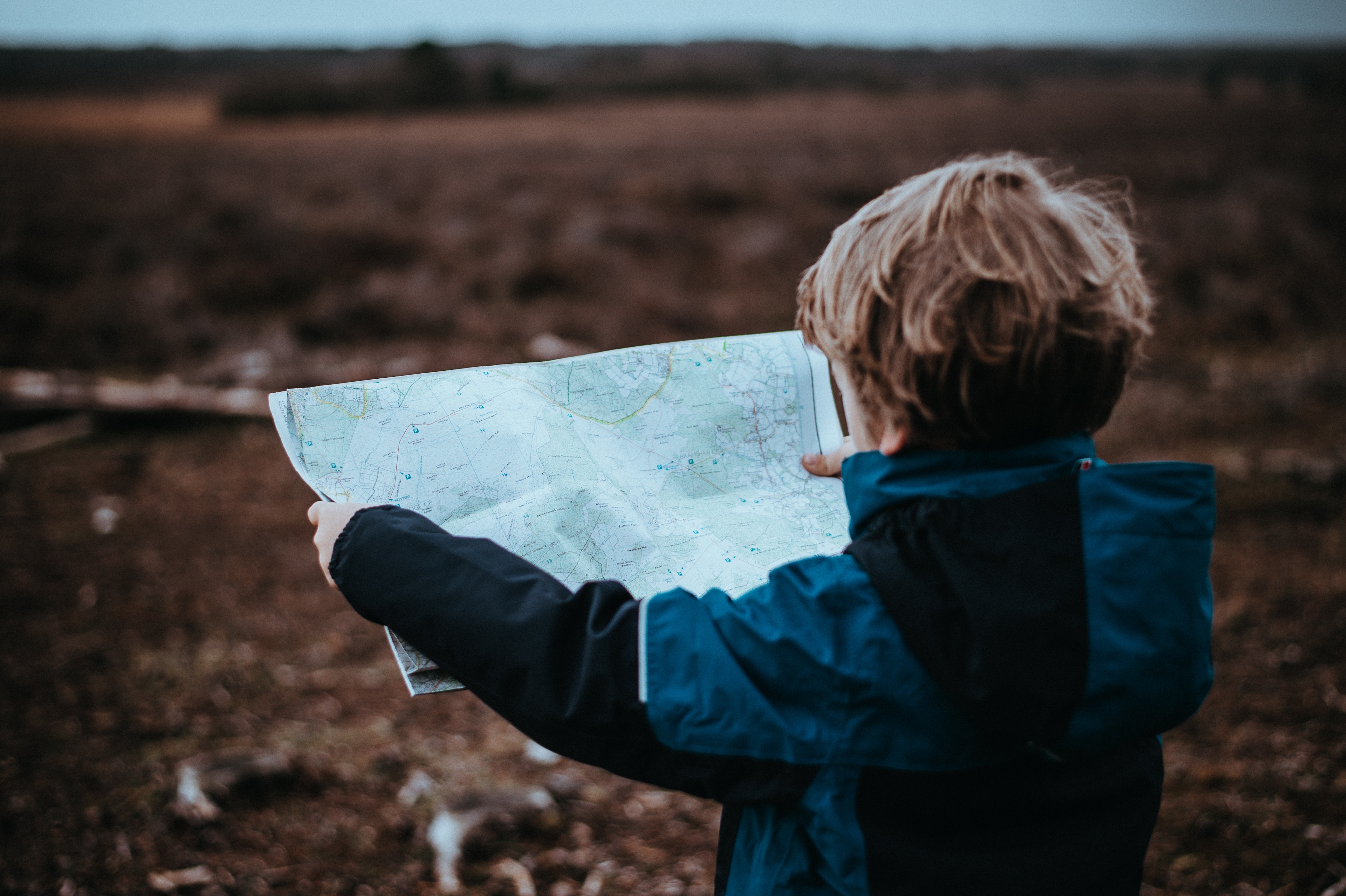 Foto eines Kindes, dass eine Karte vor einer undefinierten Landschaft hält